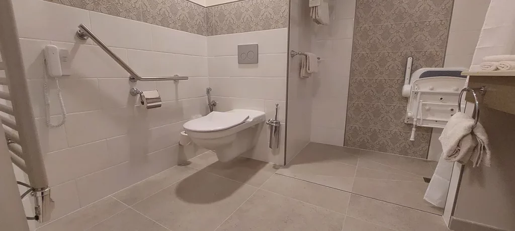 Salle de bain adaptée PMR Disneyland Hotel avec siège de douche et barres de maintien